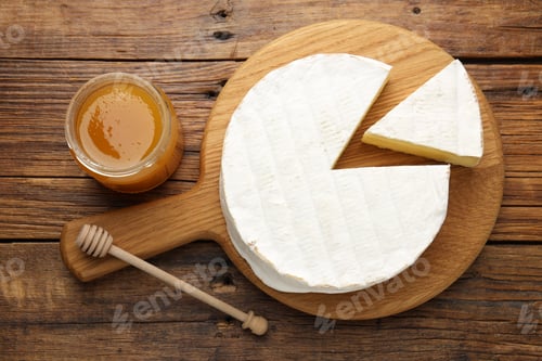 Preview: Cut delicious brie cheese, honey and dipper on wooden table, flat lay