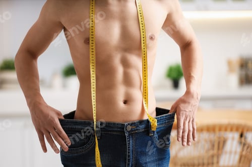 Preview: Athletic man with measuring tape wearing big jeans indoors, closeup