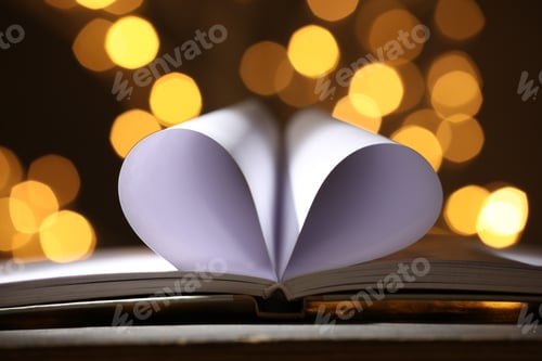 Preview: Open book with pages folded in heart shape on table against blurred lights, closeup. Bokeh effect