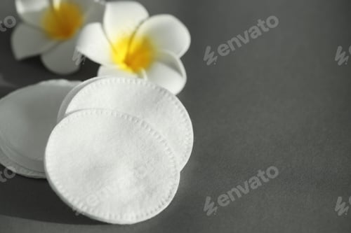 Preview: Clean cotton pads and flowers on grey background, closeup. Space for text