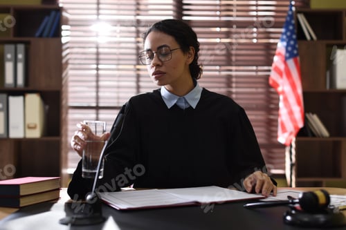 Preview: Judge with glass of water at desk indoors