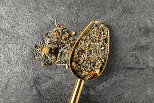 Preview: Dried green tea leaves and metal spatula on grey table, top view
