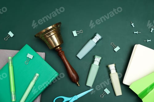 Preview: School golden bell, notebooks, markers and other stationery on green background, flat lay