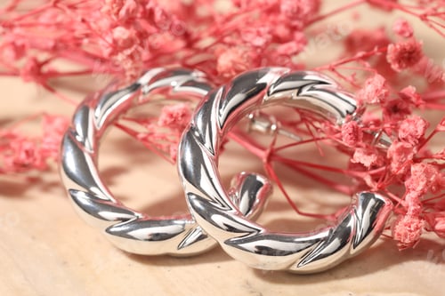 Preview: Beautiful silver earrings and flowers on light background, closeup