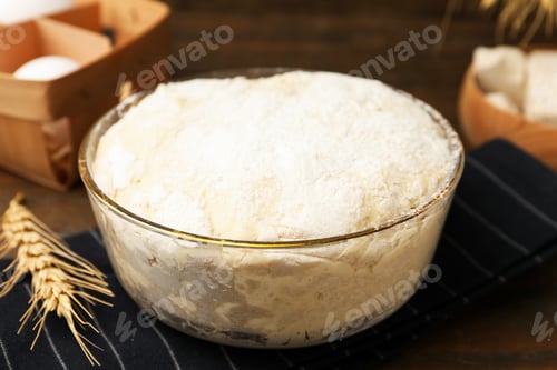 Preview: Yeast dough in glass bowl and ingredients on wooden table, closeup