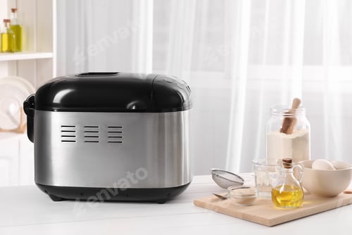 Preview: Breadmaker and different products on white wooden table indoors
