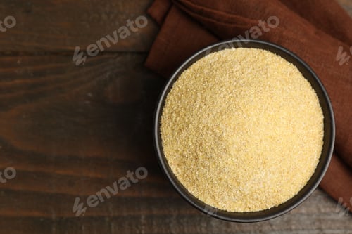 Preview: Raw semolina in bowl on wooden table, top view. Space for text