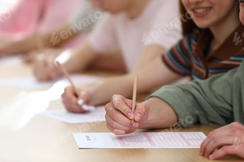 Preview: Students taking test at wooden desk in classroom, closeup
