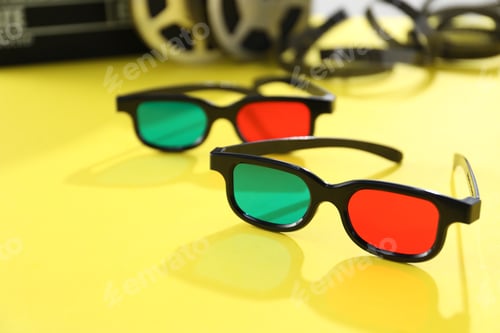 Preview: 3D glasses and film reels on yellow background, closeup. Space for text
