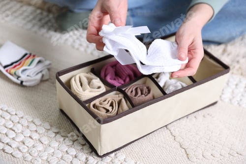 Preview: Woman putting socks into organizer on floor indoors, closeup