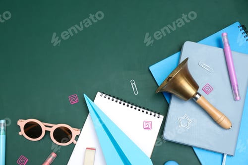 Preview: School holidays. Sunglasses, paper plane, golden bell and stationery on green background, flat lay.