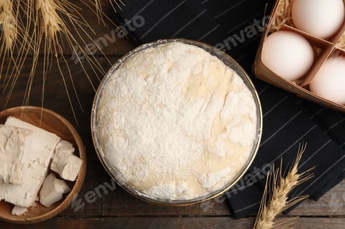 Preview: Yeast dough in glass bowl and ingredients on wooden table, flat lay