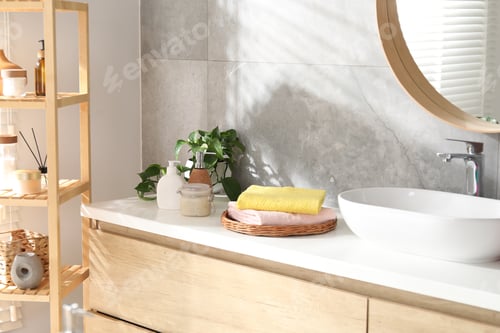 Preview: Stack of colorful towels, cosmetic products and floral decor on vanity in bathroom
