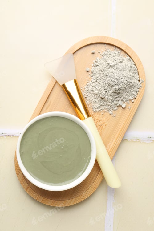 Preview: Clay powder, paste and brush on beige tiled background, top view