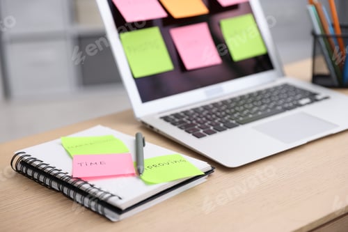 Preview: Laptop with colorful sticky notes, notebook and pen on wooden table, closeup. Multitasking, deadline