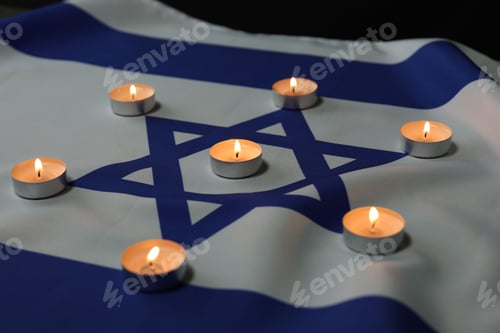 Preview: Holocaust Remembrance Day. Burning candles on flag of Israel, closeup