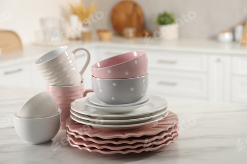 Preview: Many different clean dishware and cups on white marble table in kitchen