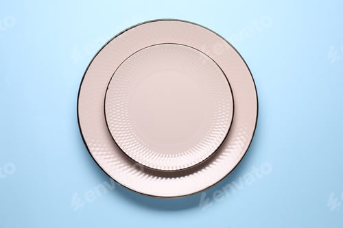 Preview: Empty plates on light blue background, top view