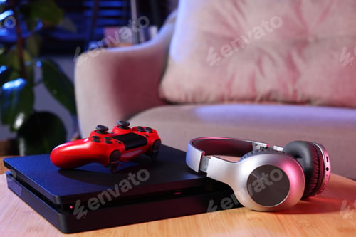 Preview: Video game console, wireless controller and headphones on wooden table indoors