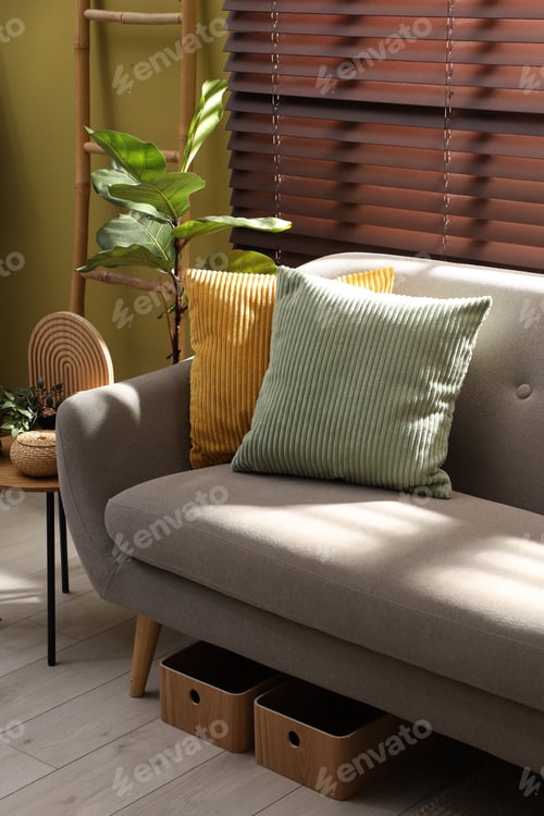 Preview: Colorful pillows on soft sofa near houseplant and end table with decor indoors