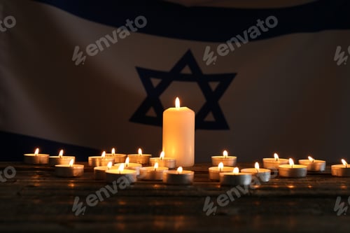 Preview: Holocaust Remembrance Day. Burning candles on table against flag of Israel