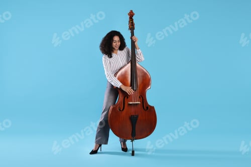 Preview: Woman playing double bass on light blue background