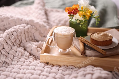 Preview: Aromatic coffee in glass cup, delicious tart, cinnamon sticks and beautiful flowers on bed, closeup.
