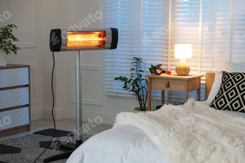 Preview: Electric heater near bed in bedroom. Domestic appliance
