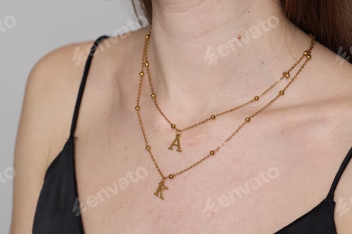 Preview: Woman wearing stylish golden necklace on light background, closeup