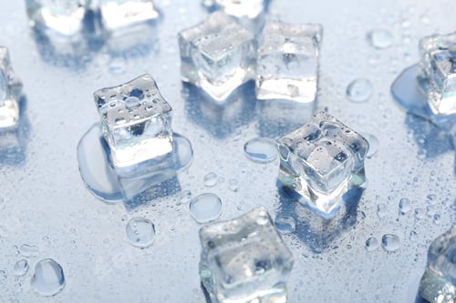 Preview: Melting ice cubes and water drops on light background, closeup