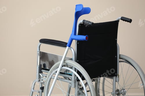 Preview: Modern wheelchair and elbow crutch near beige wall indoors. Mobility aid