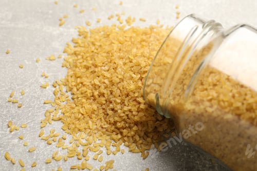 Preview: Jar with raw bulgur on light grey table, closeup