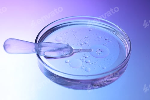 Preview: Dripping liquid from pipette into Petri dish on color background, closeup