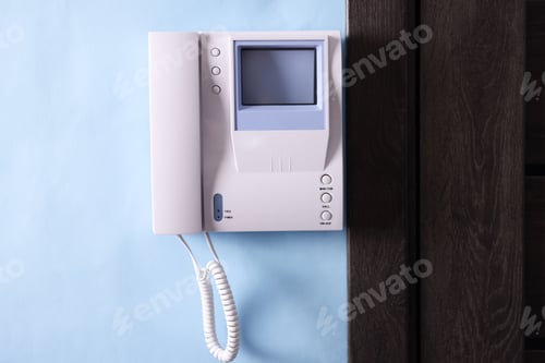 Preview: Modern intercom system with handset on light blue wall indoors