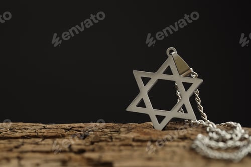 Preview: Holocaust Remembrance Day. Pendant in shape of Star of David and metal chain on wooden surface again