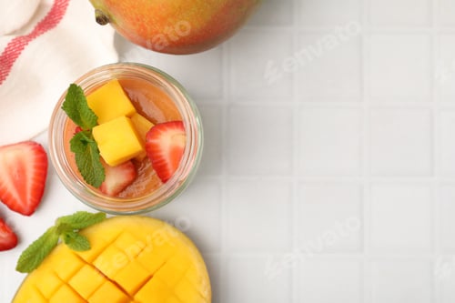 Preview: Delicious mango panna cotta, fruits and mint on white tiled table, flat lay. Space for text