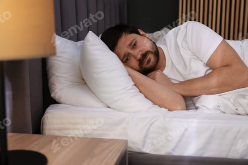Preview: Unhappy man feeling fatigue on bed at home