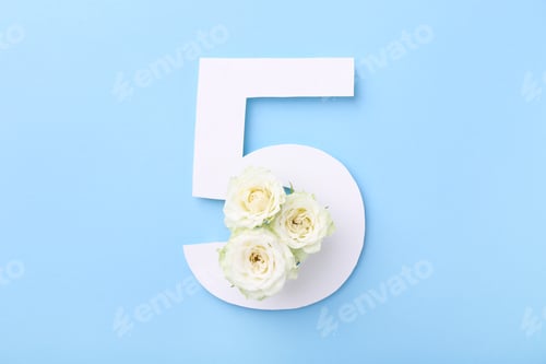 Preview: Paper number 5 and beautiful flowers on light blue background, top view