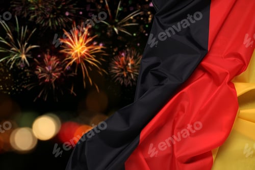 Preview: Flag of Germany against dark sky with bursting fireworks. National holiday celebration