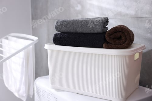 Preview: Many clean towels in laundry basket on washing machine indoors, closeup