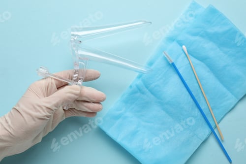 Preview: Doctor with sterile gynecological examination kit on light blue background, top view