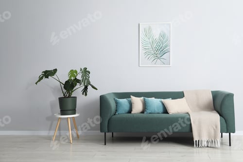 Vista previa: Comfortable sofa, green houseplant and picture indoors. Interior design