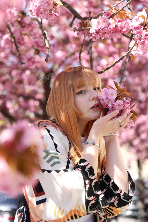 Preview: Beautiful young girl posing near blossoming sakura tree outdoors