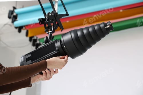 Preview: Woman with professional lighting equipment in photo studio, closeup