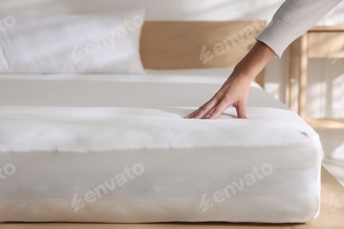 Preview: Woman touching soft mattress on bed indoors, closeup