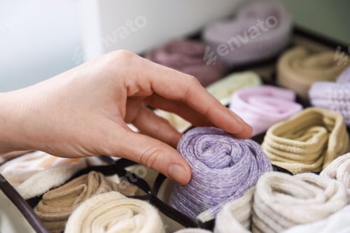 Preview: Woman putting with socks into organizer on shelf indoors, closeup
