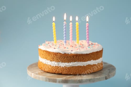 Preview: Tasty cake with colorful candles on light blue background, closeup