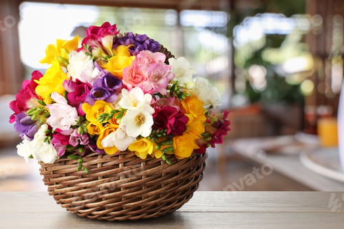 Preview: Vibrant freesia flowers in wicker basket on wooden table indoors