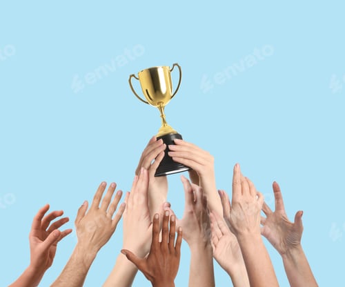 Preview: People reaching for gold cup held by winner against light blue background, closeup