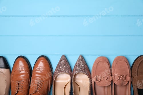 Preview: Different beautiful shoes on light blue wooden floor, flat lay. Space for text